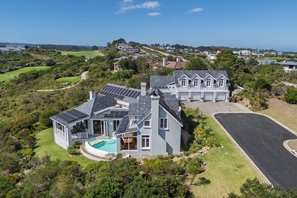 Aerial view of a luxury residence featuring a swimming pool, solar panels, slate roof, and a triple garage set within a landscaped estate.