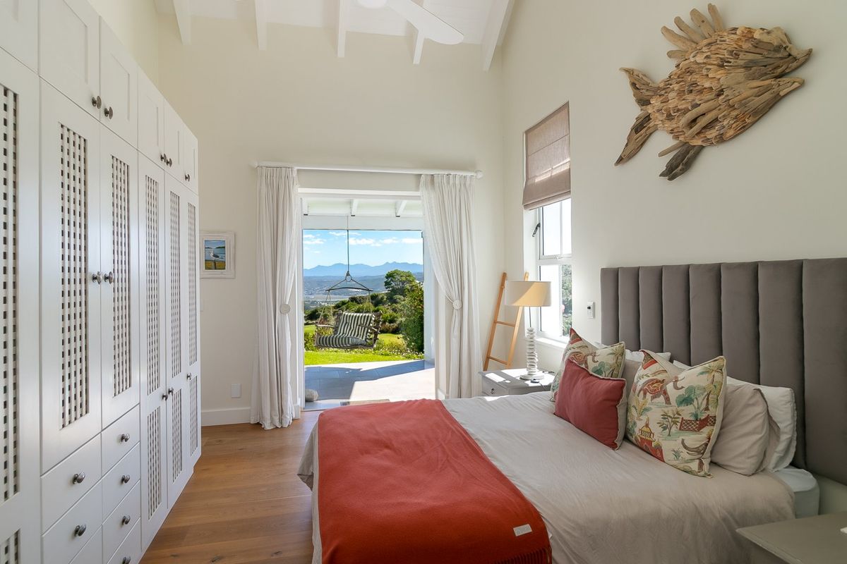 Bright bedroom featuring vaulted ceilings, extensive built-in cabinetry, hardwood floors, and direct access to a private patio with scenic mountain views.