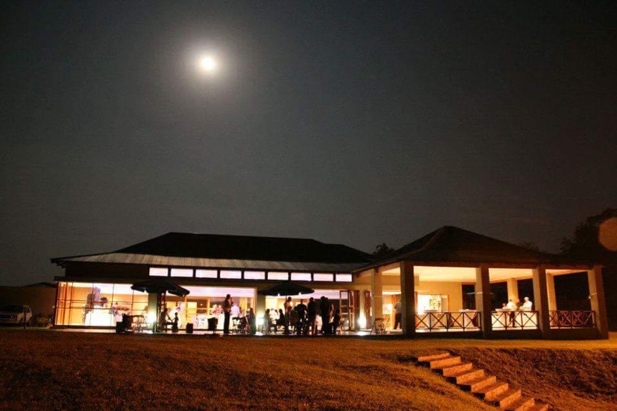Night view of the rear elevation featuring a spacious covered patio, extensive glass sliding doors, and well-lit outdoor entertainment areas.