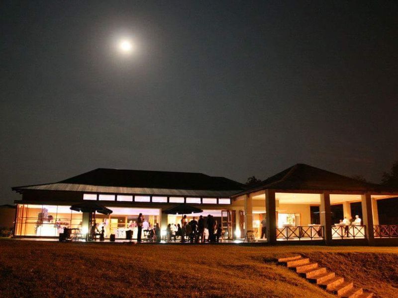 Night view of the rear elevation featuring a spacious covered patio, extensive glass sliding doors, and well-lit outdoor entertainment areas.