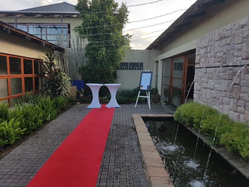 A well-maintained outdoor courtyard featuring a stone-clad wall, a built-in water feature, and paved flooring, suitable for events or outdoor relaxation.