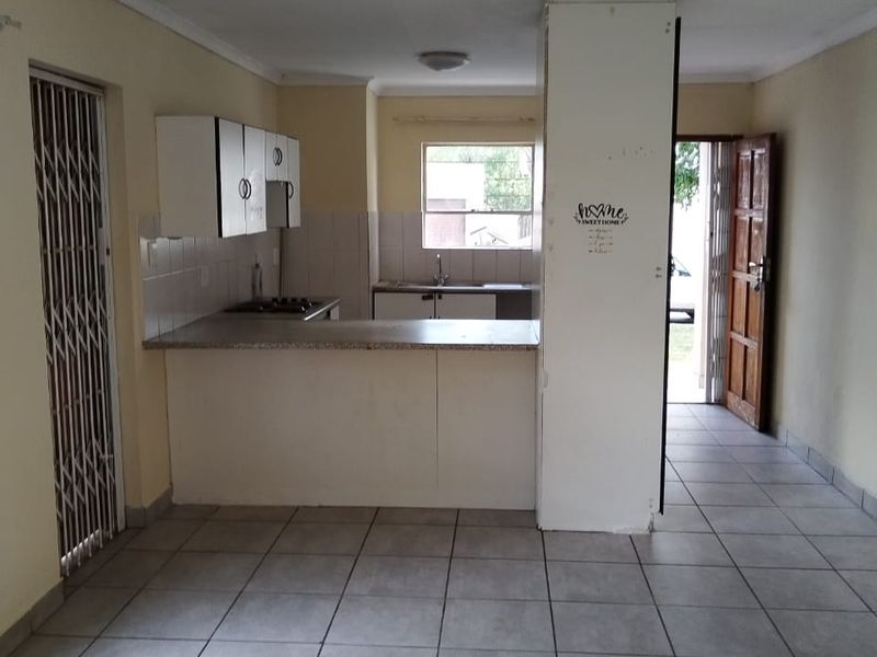 Open plan kitchen and living area featuring tiled flooring, built-in cabinetry, and direct access to the exterior via a security gate.