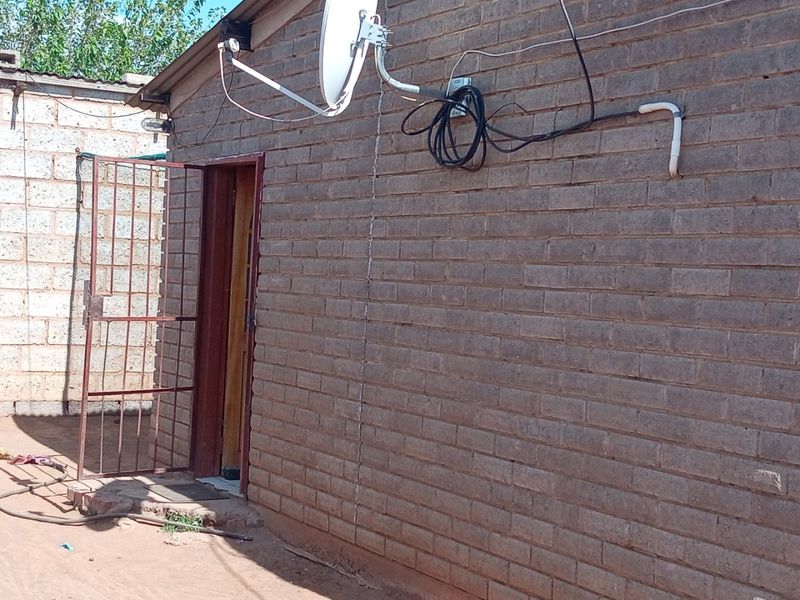 Rear exterior view of the property featuring exposed brick walls, a security gate, and mounted satellite dish infrastructure.