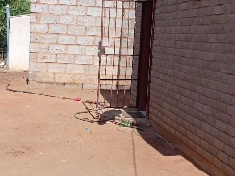 Rear exterior view of a brick structure featuring a security gate and satellite dish installation.
