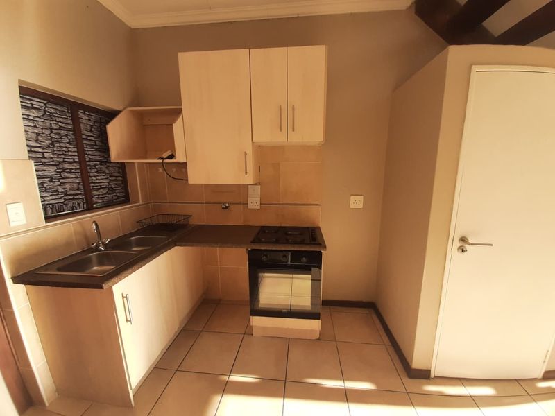 A functional kitchen featuring built-in cabinetry, a double sink, a built-in oven with hob, and tiled flooring.