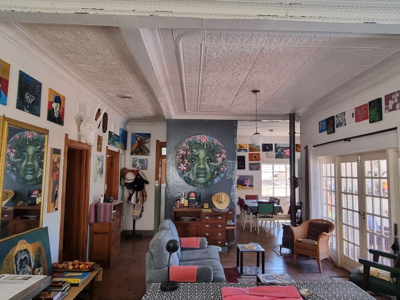 Open plan living and dining area featuring characterful pressed metal ceilings, hardwood flooring, a wood-burning stove, and access to the outdoors via french doors.