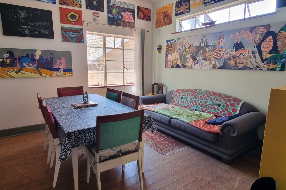 A living and dining area featuring original timber flooring, steel-framed windows, and high-level clerestory windows providing natural light.