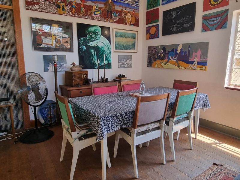 Dining room featuring timber flooring and a steel-framed window with security mesh, offering a functional space for family meals.