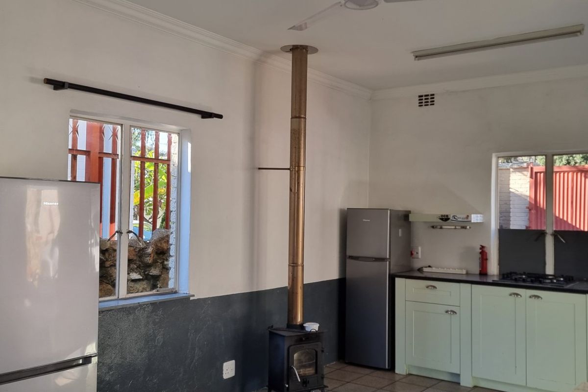 Kitchen area featuring built-in cabinetry, a gas hob, and a prominent wood-burning stove, with tiled flooring and security bars on the windows.