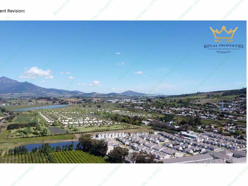 An aerial view of a residential estate surrounded by scenic landscape and mountain ranges.