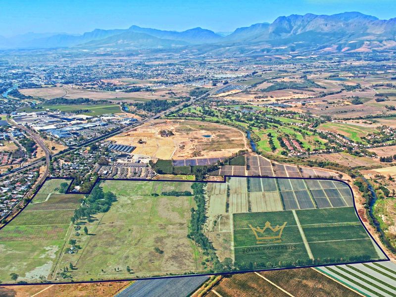 An aerial view of a large, expansive vacant residential land parcel with clear boundary lines, set against a scenic mountain and valley backdrop.