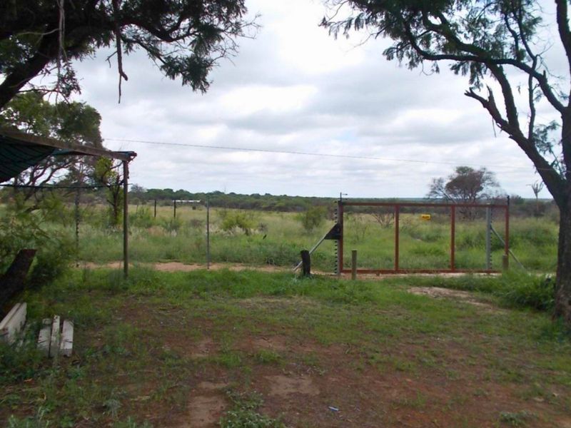 A view of the farm property boundary featuring a metal gate and wire fencing set against an open landscape.