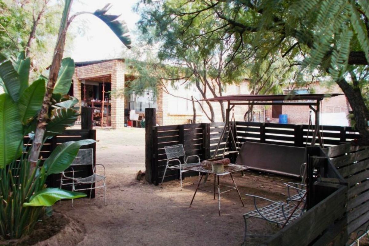 A rear garden area featuring timber slat fencing and a view towards the exposed brick facade of the main dwelling.