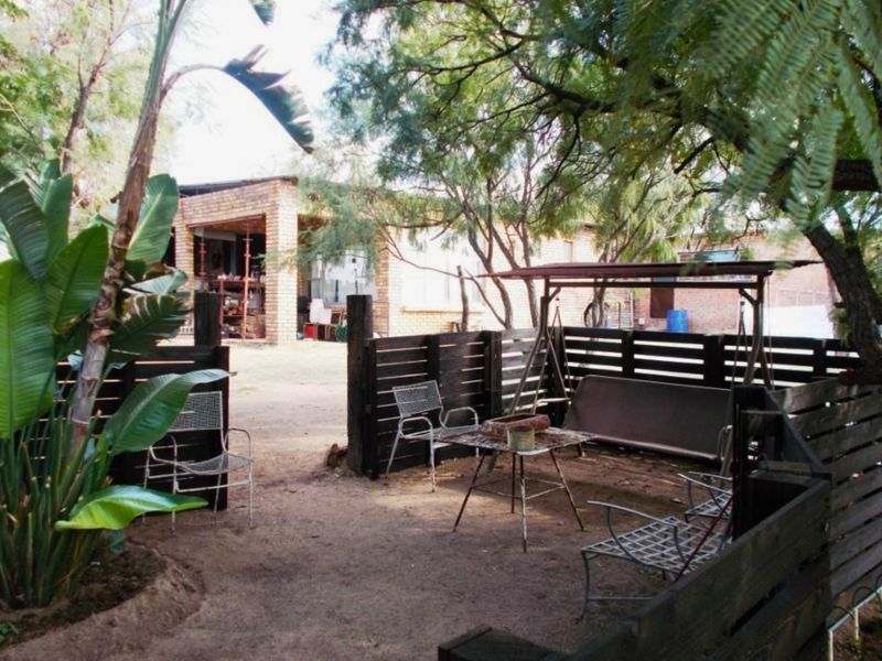 A rear garden area featuring timber slat fencing and a view towards the exposed brick facade of the main dwelling.