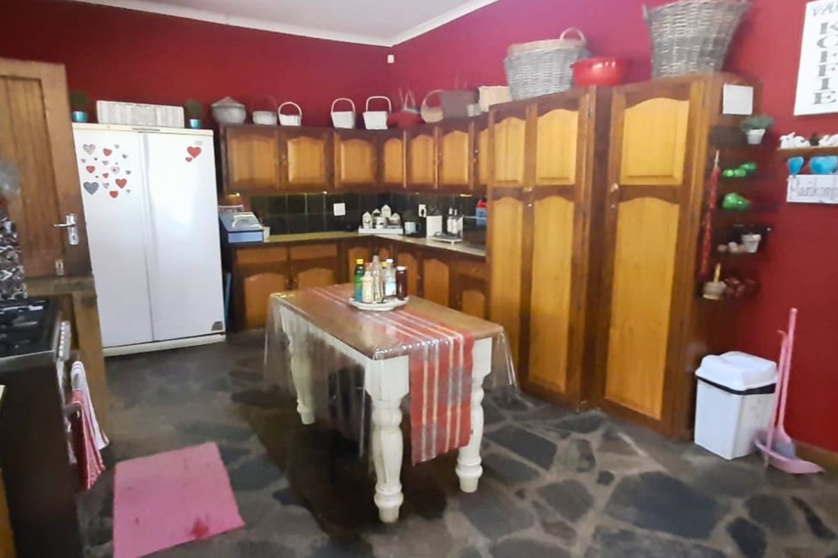 Rustic kitchen featuring traditional wooden cabinetry, stone flooring, and a tiled backsplash, offering a warm and functional farm-style cooking space.