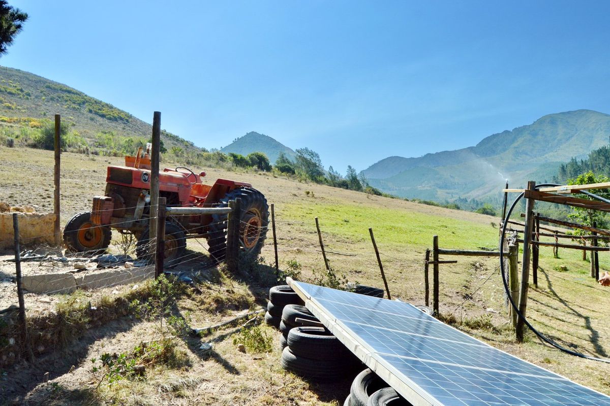 Expansive farm landscape featuring solar panels, irrigation infrastructure, and mountain views, showcasing the property's agricultural utility and natural surroundings.