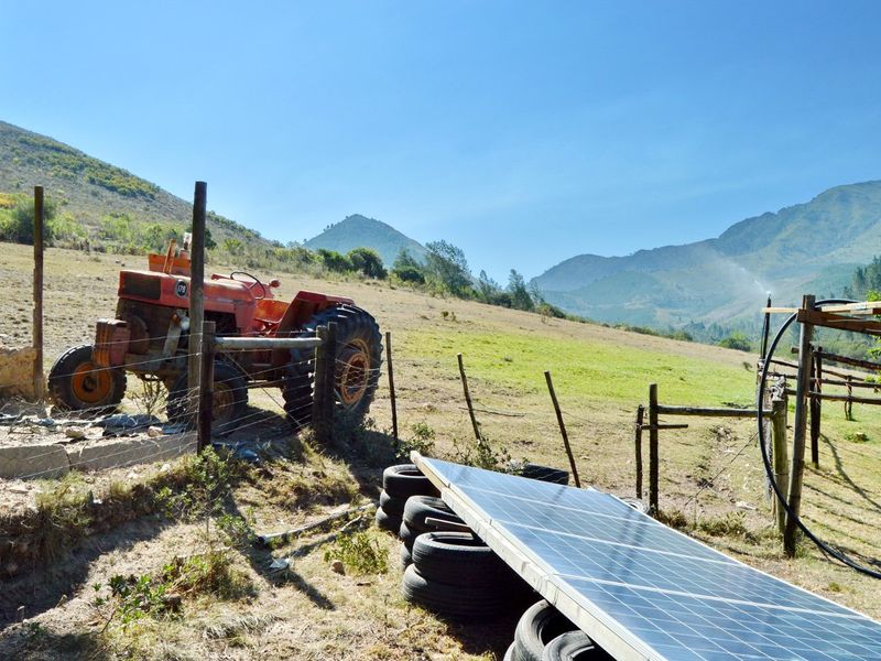 Expansive farm landscape featuring solar panels, irrigation infrastructure, and mountain views, showcasing the property's agricultural utility and natural surroundings.