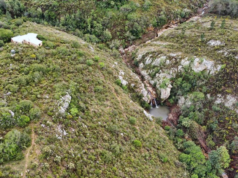 Aerial view of the farm property showcasing the natural landscape, rocky terrain, and a scenic waterfall feature.