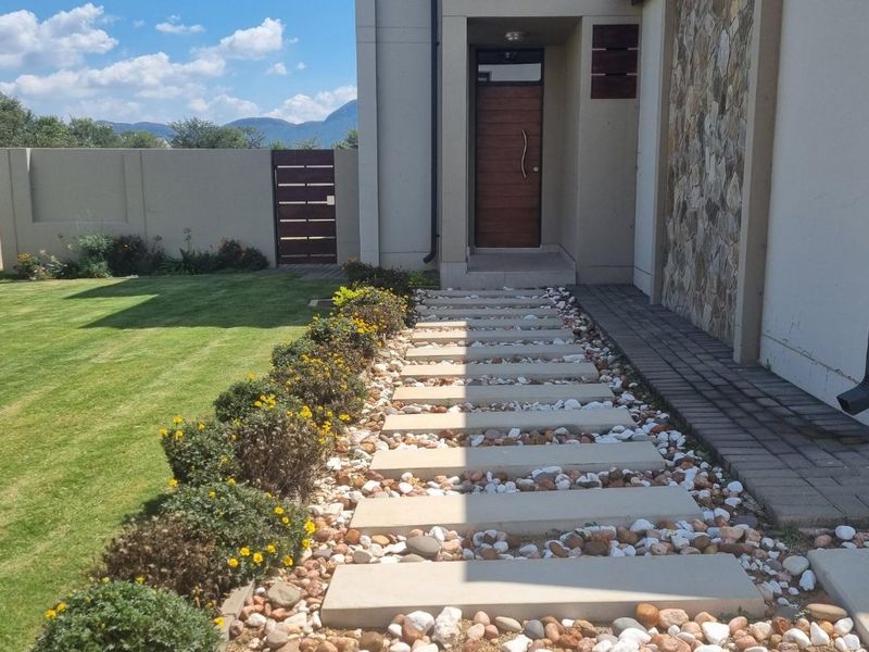 Front entrance of the townhouse featuring a modern timber door, stone feature wall, and a landscaped walkway with concrete pavers and decorative pebbles.