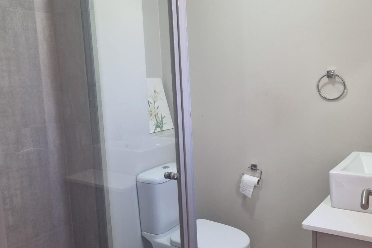 A modern bathroom featuring a glass-enclosed shower, a contemporary vanity basin, and neutral floor-to-ceiling tiling.