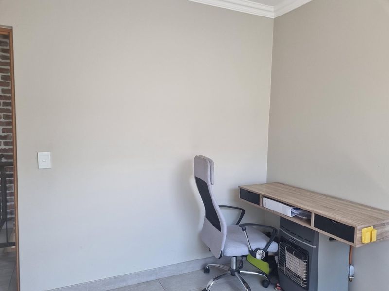 A functional home office space featuring neutral wall tones, tiled flooring, and decorative coving.