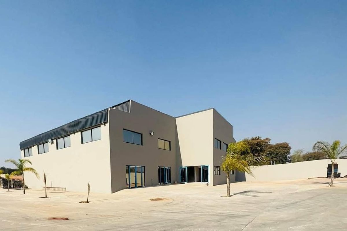 Modern commercial building featuring a clean facade, metal roofing, and large aluminium-framed windows set within a spacious paved yard.