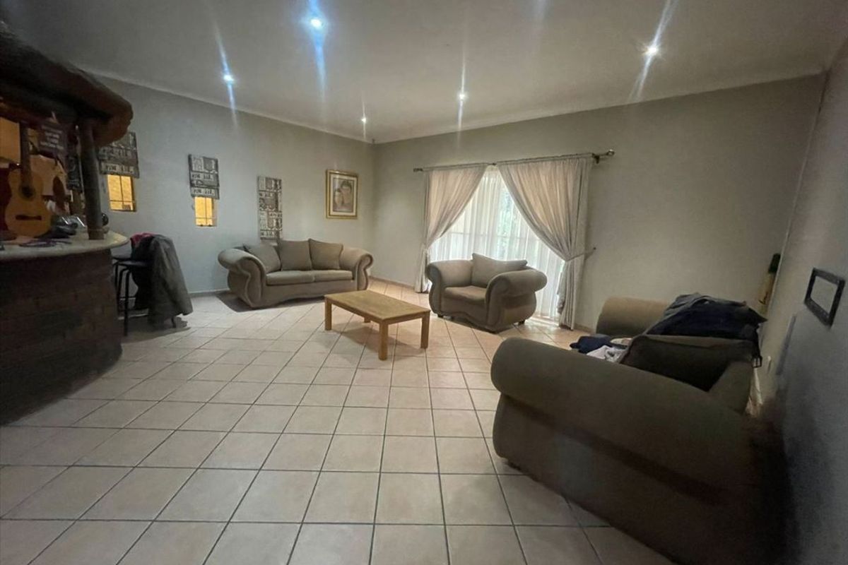 Spacious living room featuring tiled flooring, recessed downlighting, and a built-in bar area, offering a versatile layout for relaxation and entertainment.