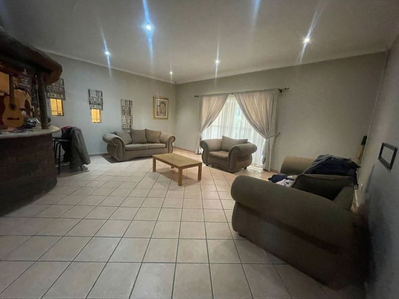 Spacious living room featuring tiled flooring, recessed downlighting, and a built-in bar area, offering a versatile layout for relaxation and entertainment.