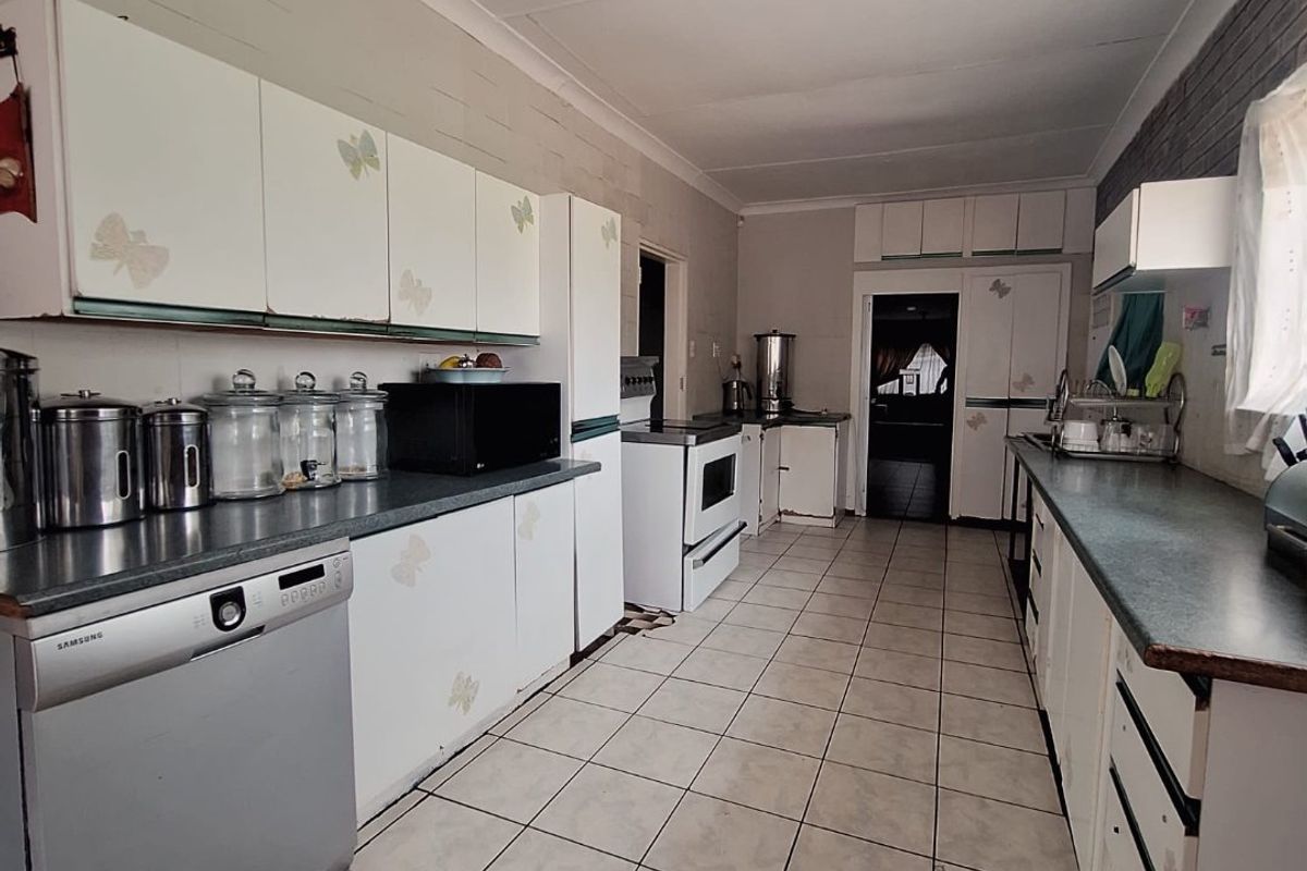 A functional galley-style kitchen featuring white cabinetry, laminate countertops, and ceramic tile flooring, offering a dated aesthetic ready for modernization.