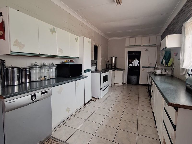 A functional galley-style kitchen featuring white cabinetry, laminate countertops, and ceramic tile flooring, offering a dated aesthetic ready for modernization.