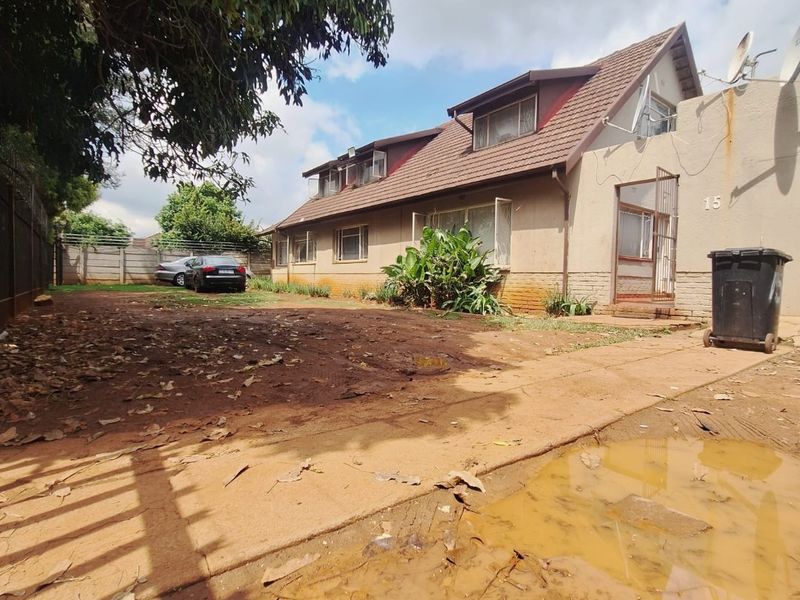 Front exterior view of a two-story house featuring a tiled roof, dormer windows, and an unpaved driveway area requiring landscaping.