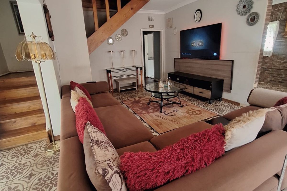 A living room featuring patterned floor tiles, a wooden staircase, and exposed brick accents, creating a distinct character space.