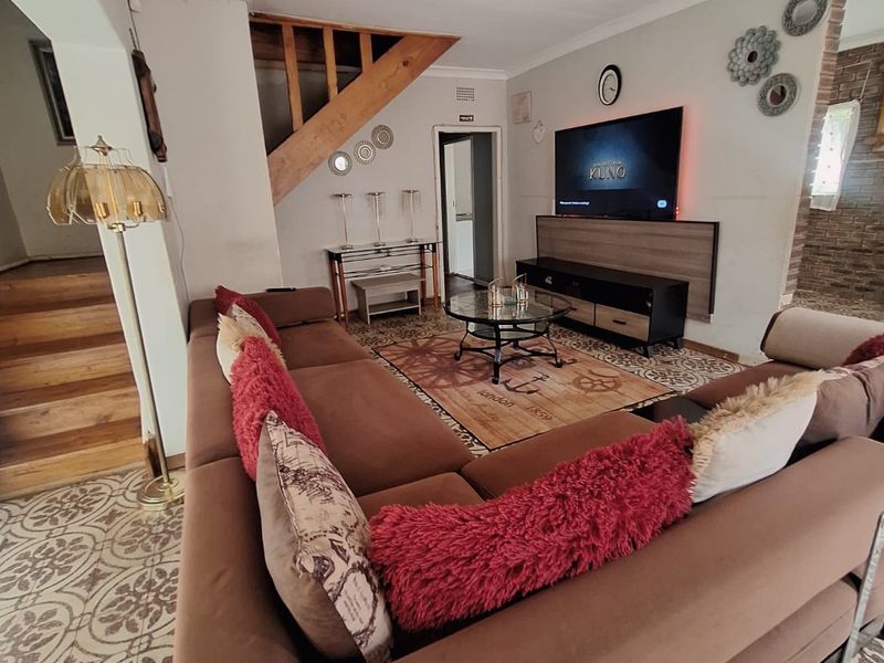 A living room featuring patterned floor tiles, a wooden staircase, and exposed brick accents, creating a distinct character space.