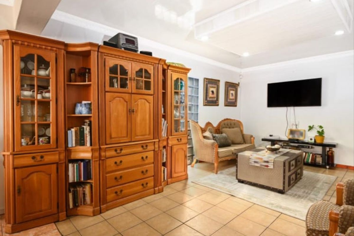 A living room featuring tiled flooring, recessed ceiling lighting, and a unique glass block window feature, providing a functional and well-lit living space.
