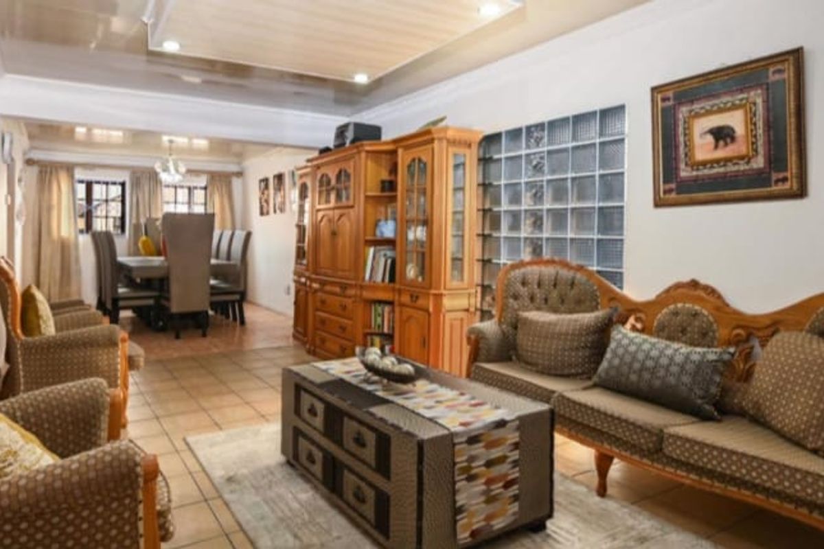 An open-plan living and dining area featuring tiled flooring, a decorative glass block wall, and recessed ceiling lighting.