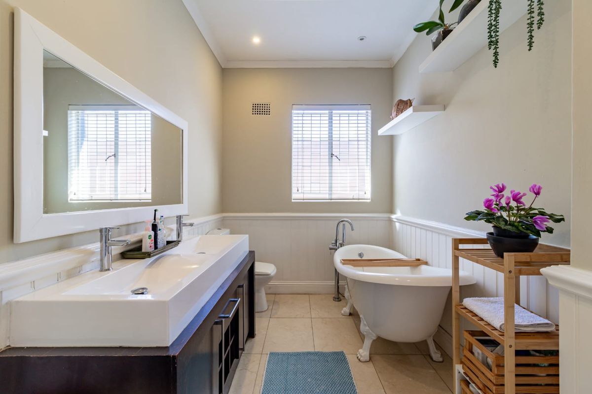 A well-appointed bathroom featuring a double vanity, a classic freestanding clawfoot bathtub, and elegant wainscoting detail.