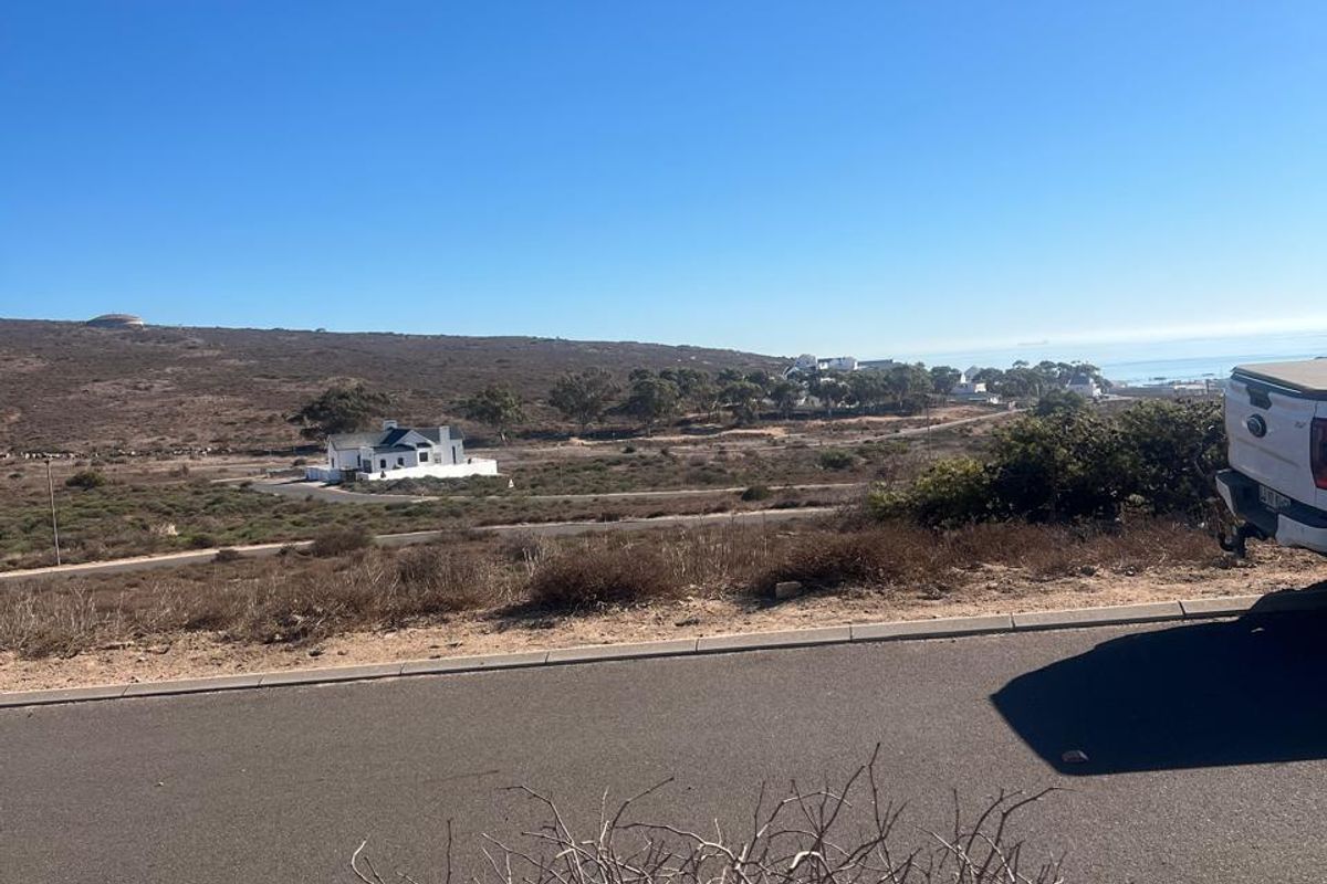 A wide-angle view of the surrounding coastal landscape and residential area from the perspective of a vacant residential plot.