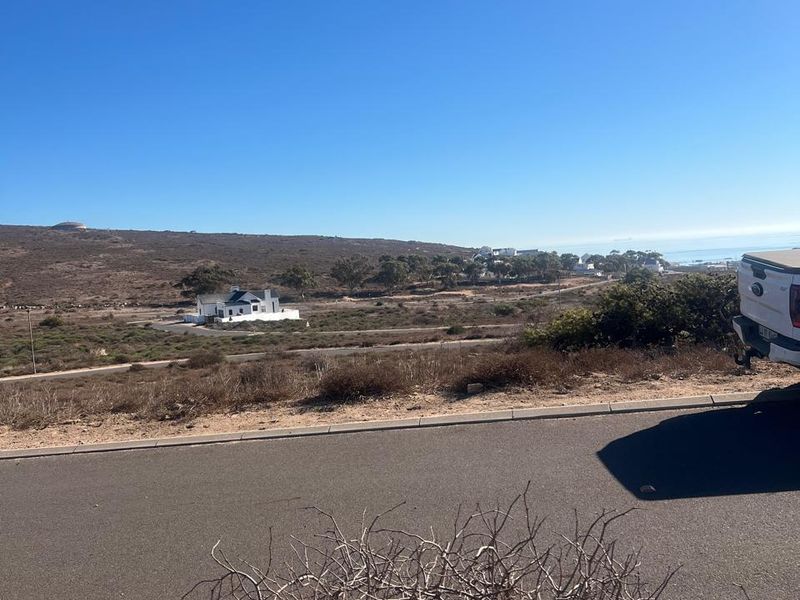 A wide-angle view of the surrounding coastal landscape and residential area from the perspective of a vacant residential plot.