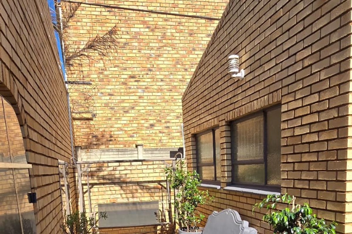 A private, paved rear courtyard enclosed by face brick walls, featuring integrated security lighting and a low-maintenance outdoor space.