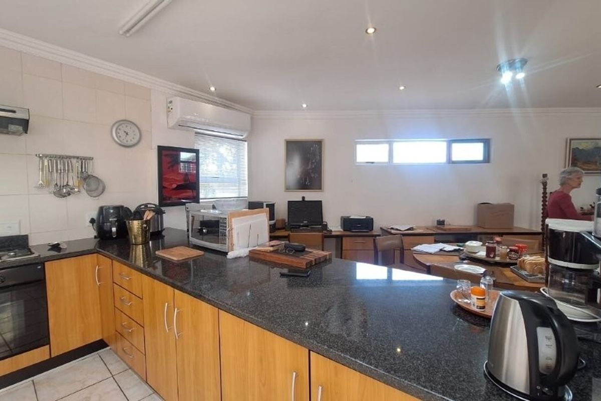 A functional kitchen featuring granite countertops, built-in cabinetry, a gas hob with extractor fan, and tiled flooring, with an integrated air conditioning unit.