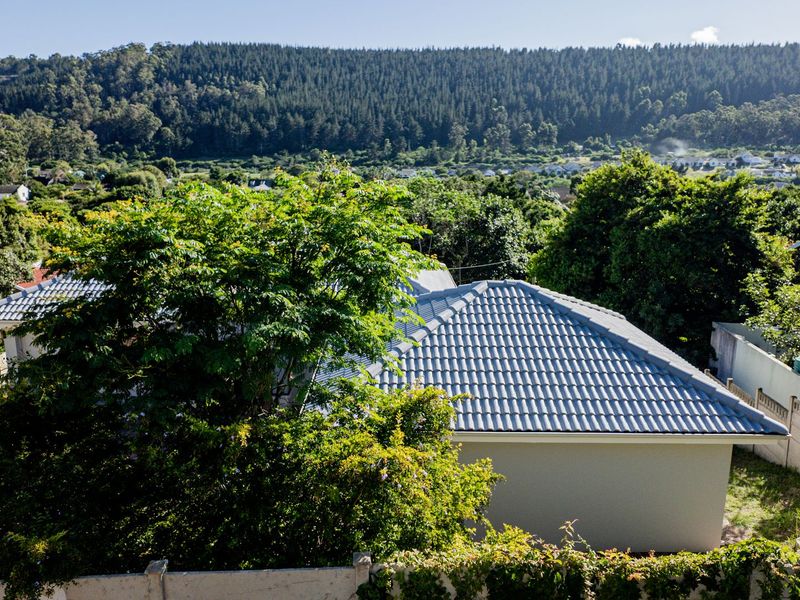 An elevated aerial view of the property showing the tiled roof structure and surrounding residential landscape with a scenic mountain backdrop.