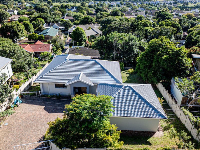 Aerial view of a residential property featuring a tiled roof, paved driveway, and established garden within a suburban neighborhood setting.