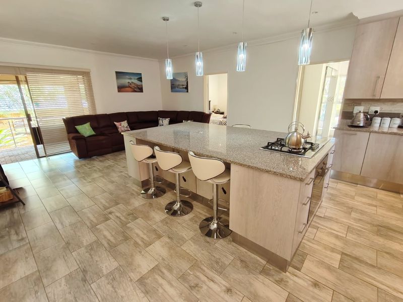 Spacious open-plan living area featuring a modern kitchen with a large granite island, gas hob, and seamless flow to the outdoor patio.