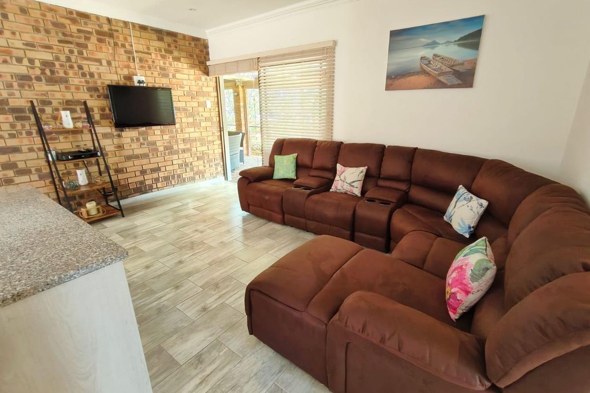 A comfortable living room featuring an exposed brick accent wall, modern tiled flooring, and direct access to an outdoor patio area.