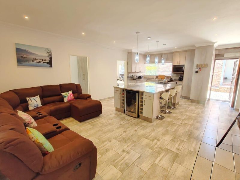 Spacious open-plan living area featuring a modern kitchen with a large island, stone countertops, built-in wine cooler, and contemporary tiled flooring throughout.
