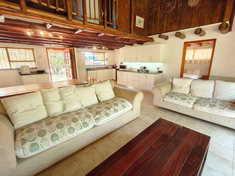 Open-plan living and kitchen area featuring exposed timber ceiling beams, a mezzanine loft level, and tiled flooring throughout.