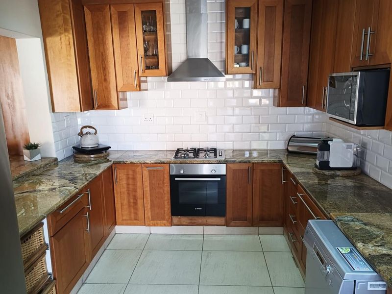 A functional kitchen featuring wooden cabinetry, granite countertops, a subway tile backsplash, and integrated stainless steel appliances.