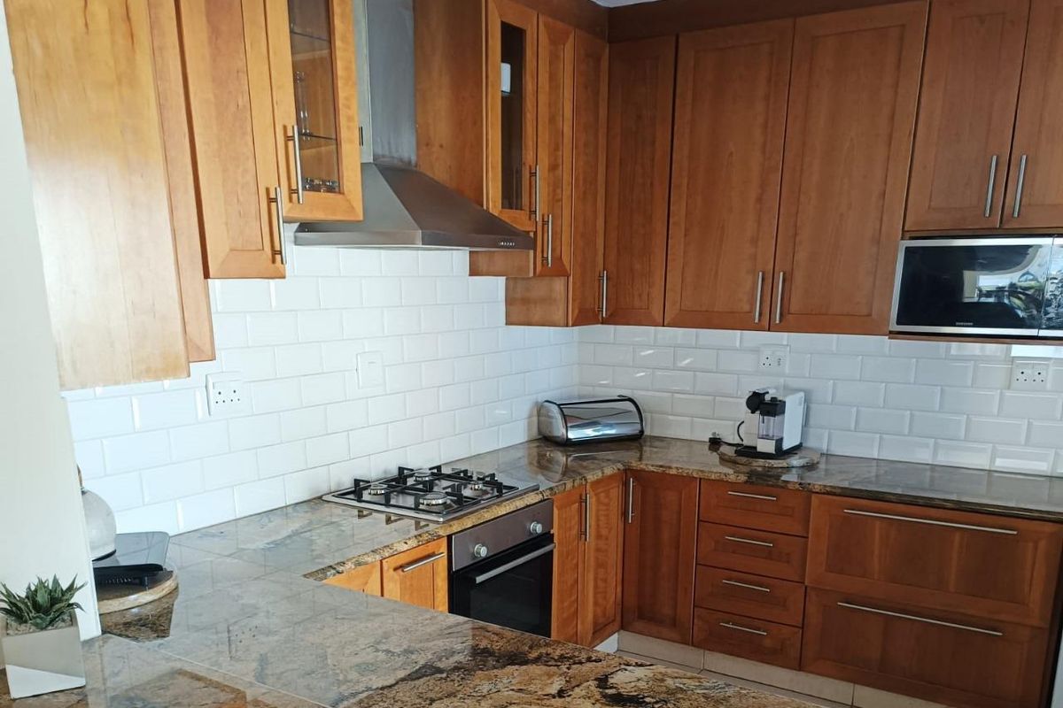 A functional kitchen featuring warm wooden cabinetry, granite countertops, a subway tile backsplash, and integrated stainless steel appliances.