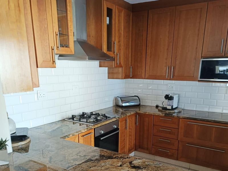 A functional kitchen featuring warm wooden cabinetry, granite countertops, a subway tile backsplash, and integrated stainless steel appliances.