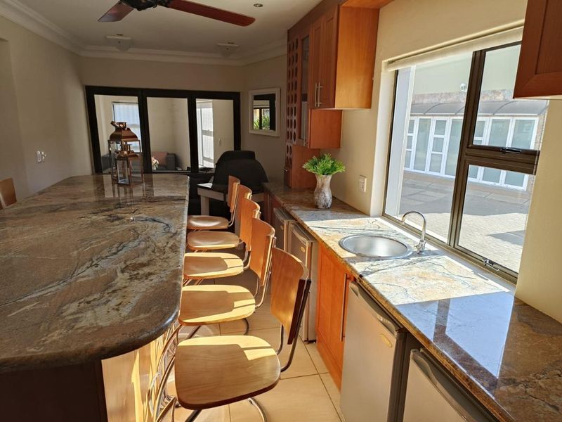 A well-appointed kitchen area featuring granite countertops, wooden cabinetry, and a breakfast bar, offering a functional space for food preparation and casual dining.